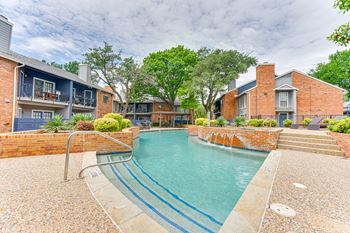 A small pool surrounded by a brick wall and steps leading to a house.